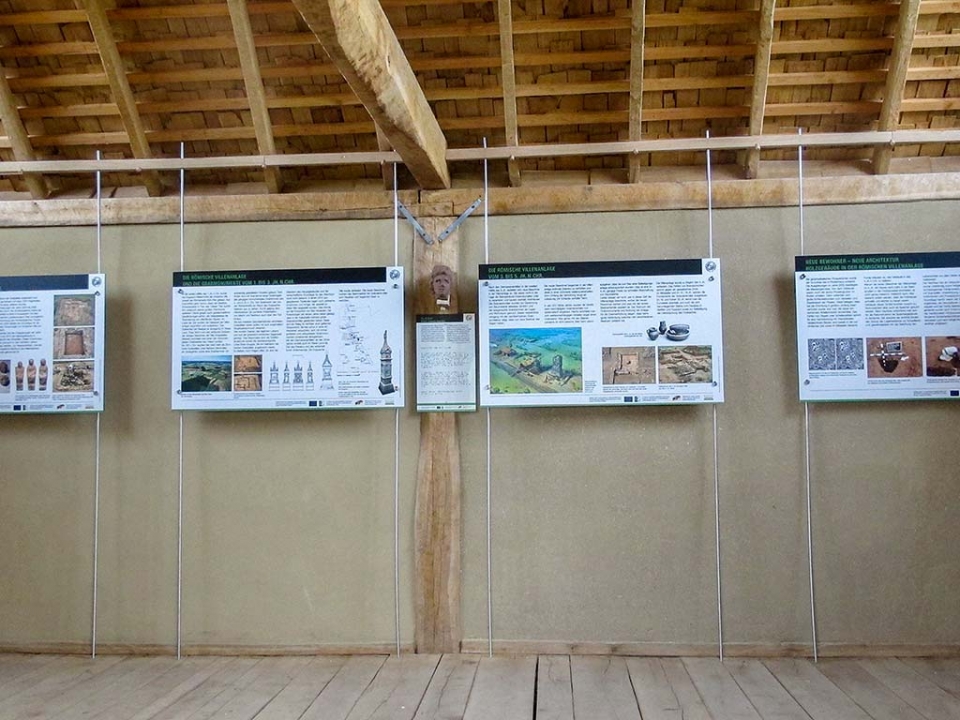 Blick vom Eingang in das Gebäude mit Infotafeln und einer Replik.